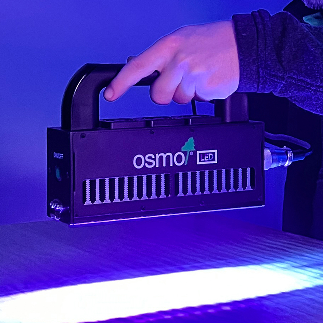 Professional holding UV LED lamp to instantly dry LED Smart Oil hardwax oil for flooring and furniture. Sold by Osmo Canada.