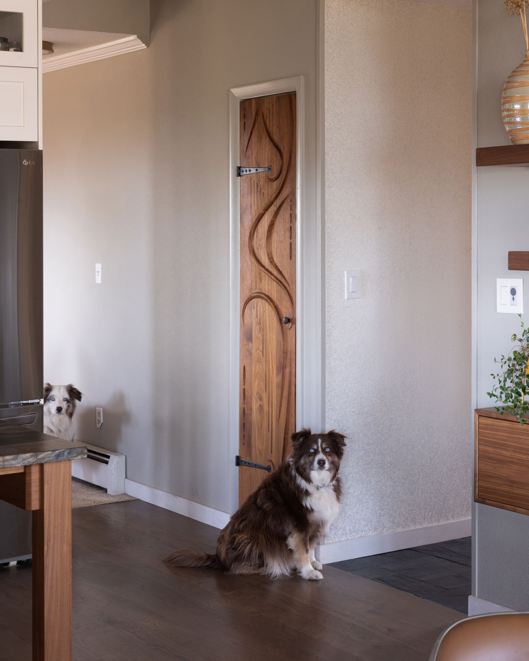 Horror Vacui – Ash Pales Interior Design and two dogs standing in front of a sculptural wood door.